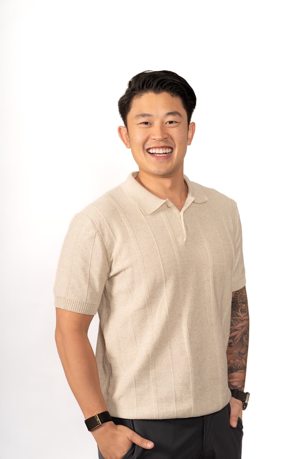 Mervin Truong smiling in a cream knit polo against a white studio backdrop